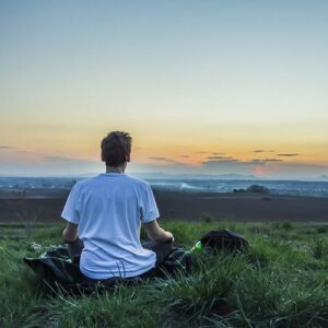 man meditating to calm the mind overlooking the ocean and sunset