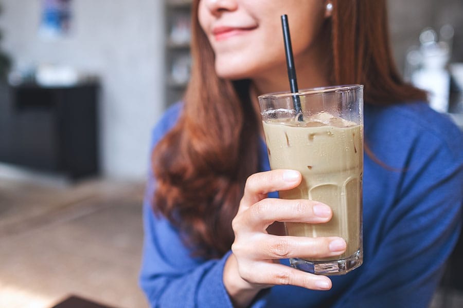 woman enjoying a cup of iced kava in her home