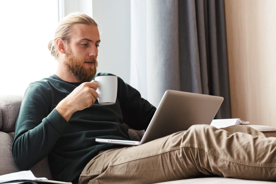 Male enjoying a cup of Kava while on computer